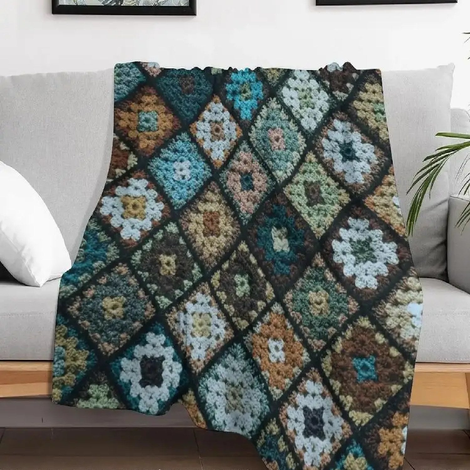Plaid patchwork multicolore effet crochet drapé sur un canapé gris dans un salon avec plante verte