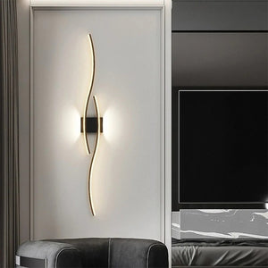 Applique murale noire double courbe LED accrochée verticalement sur un mur en bois clair près d'un téléviseur