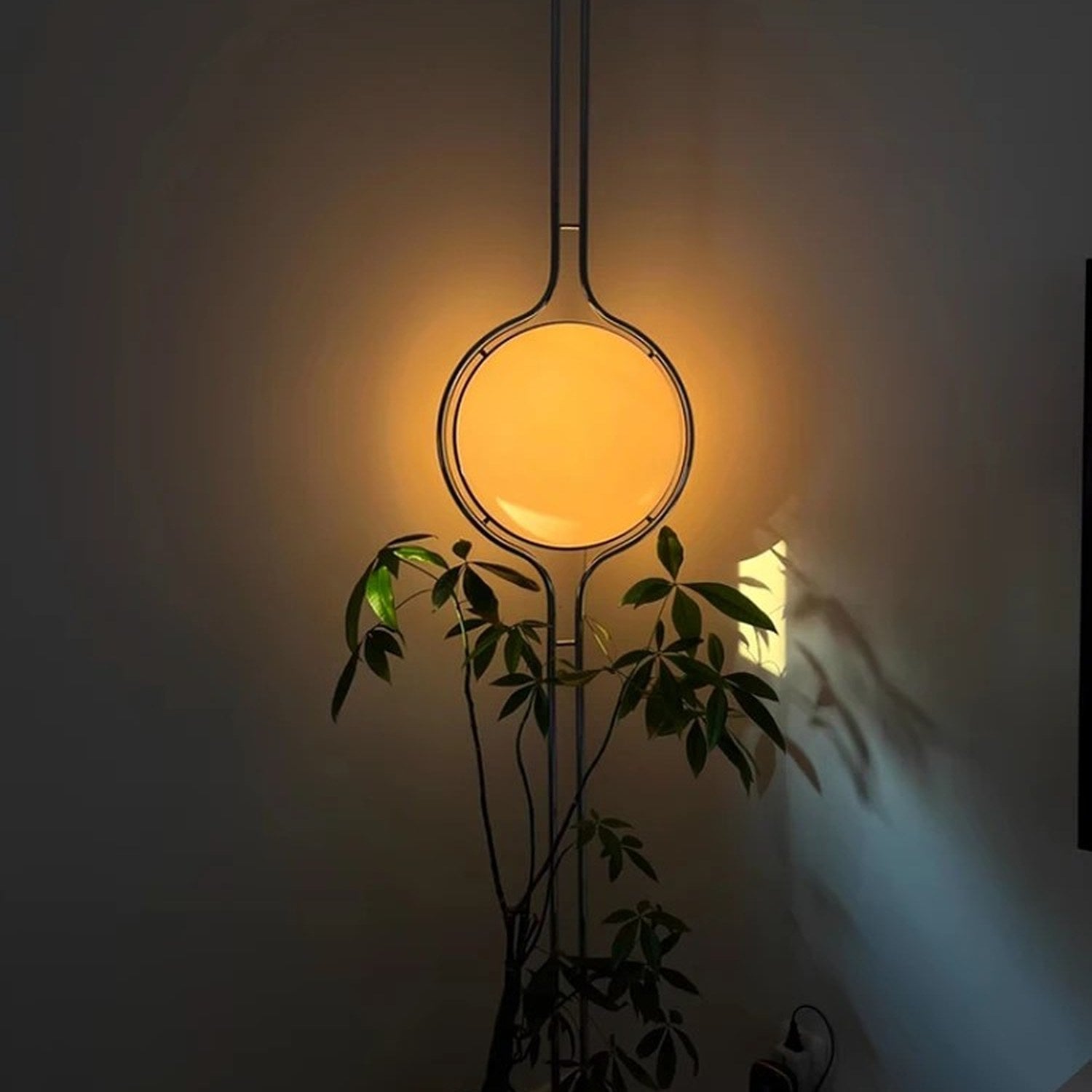 Lampadaire colonne chrome diffusant une lueur chaude dans un intérieur tamisé