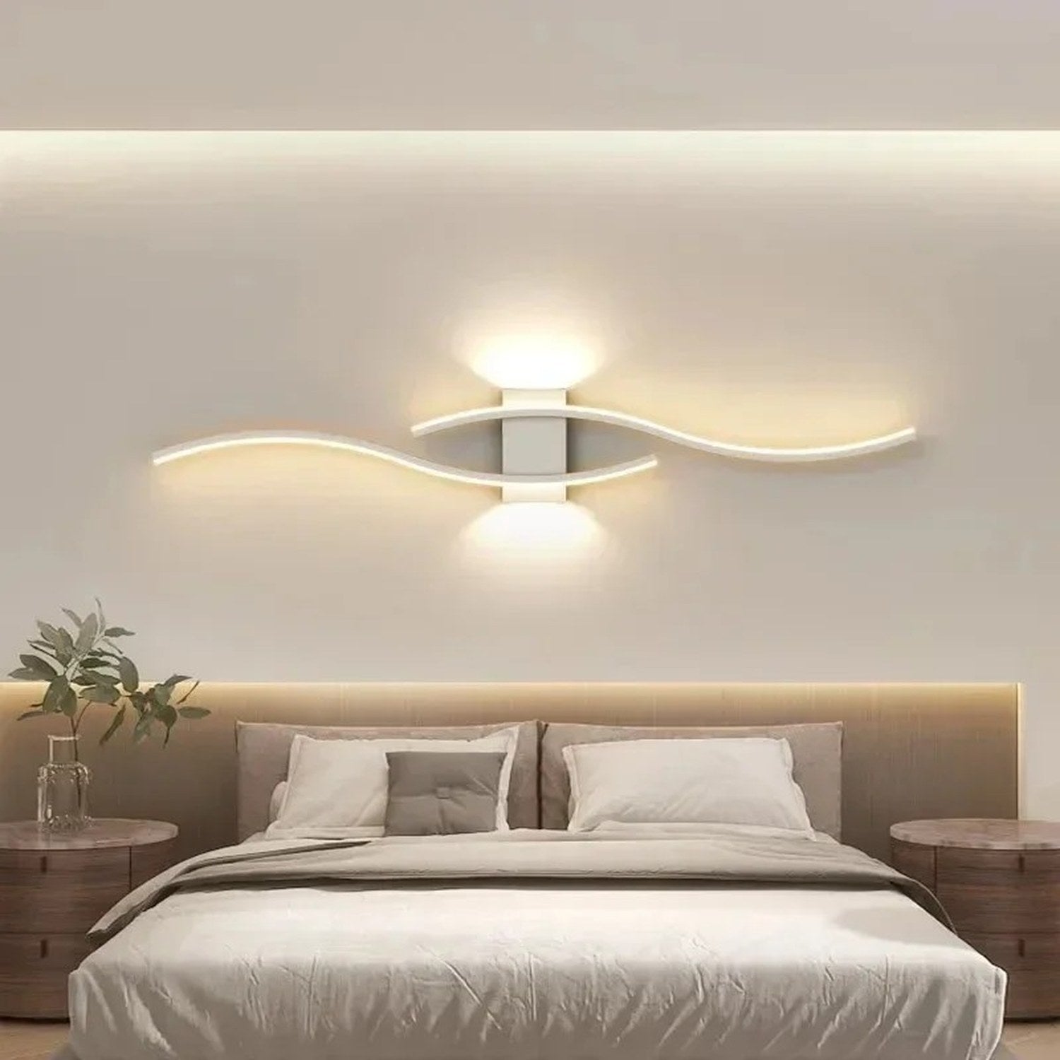 Applique murale blanche double courbe LED au dessus d'une tête de lit avec une plante verte