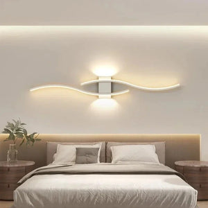Applique murale blanche double courbe LED au dessus d'une tête de lit avec une plante verte