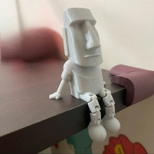 Statue Moai assise au bord d'une tablette les jambes articulées pendantes