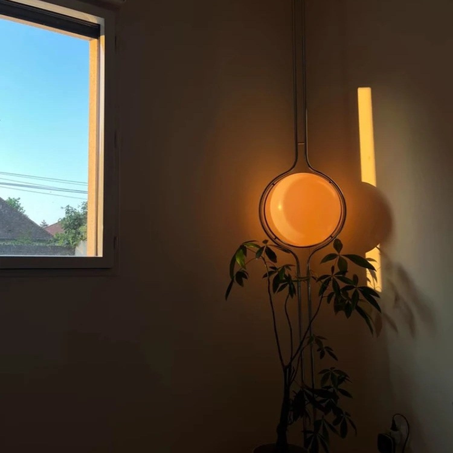 Lampadaire boule allumé au coucher du soleil près d'une fenêtre