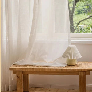 Voilage beige translucide drapé près d'une fenêtre ensoleillée