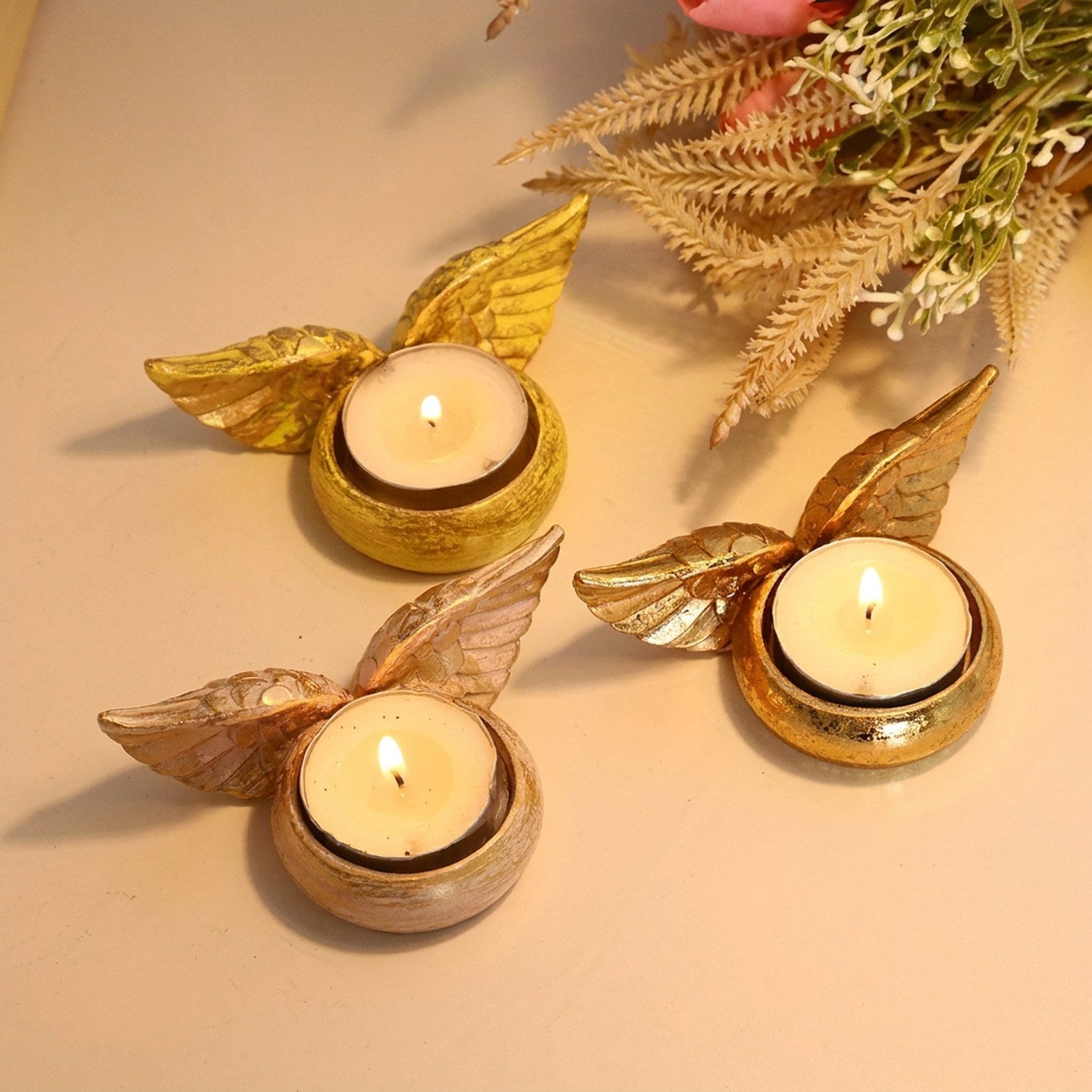 Trois bougeoirs ailes d'ange résine couleurs doré rose jaune avec bougies allumées décoration
