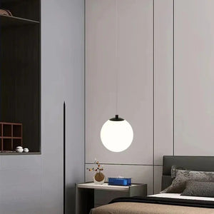 Suspension boule en verre opalin noire suspendue au-dessus d'une table de chevet
