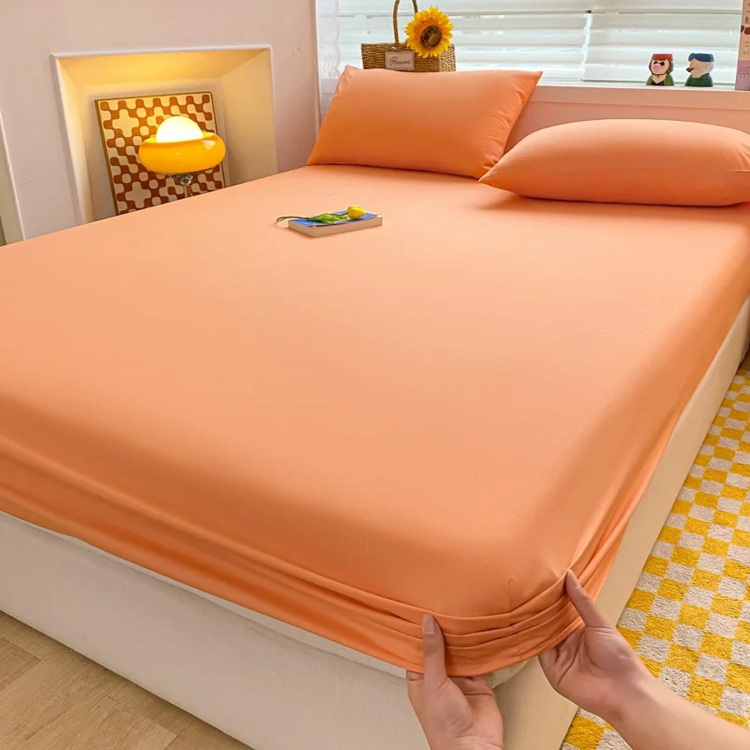 Drap housse orange installé sur un lit avec oreillers assortis