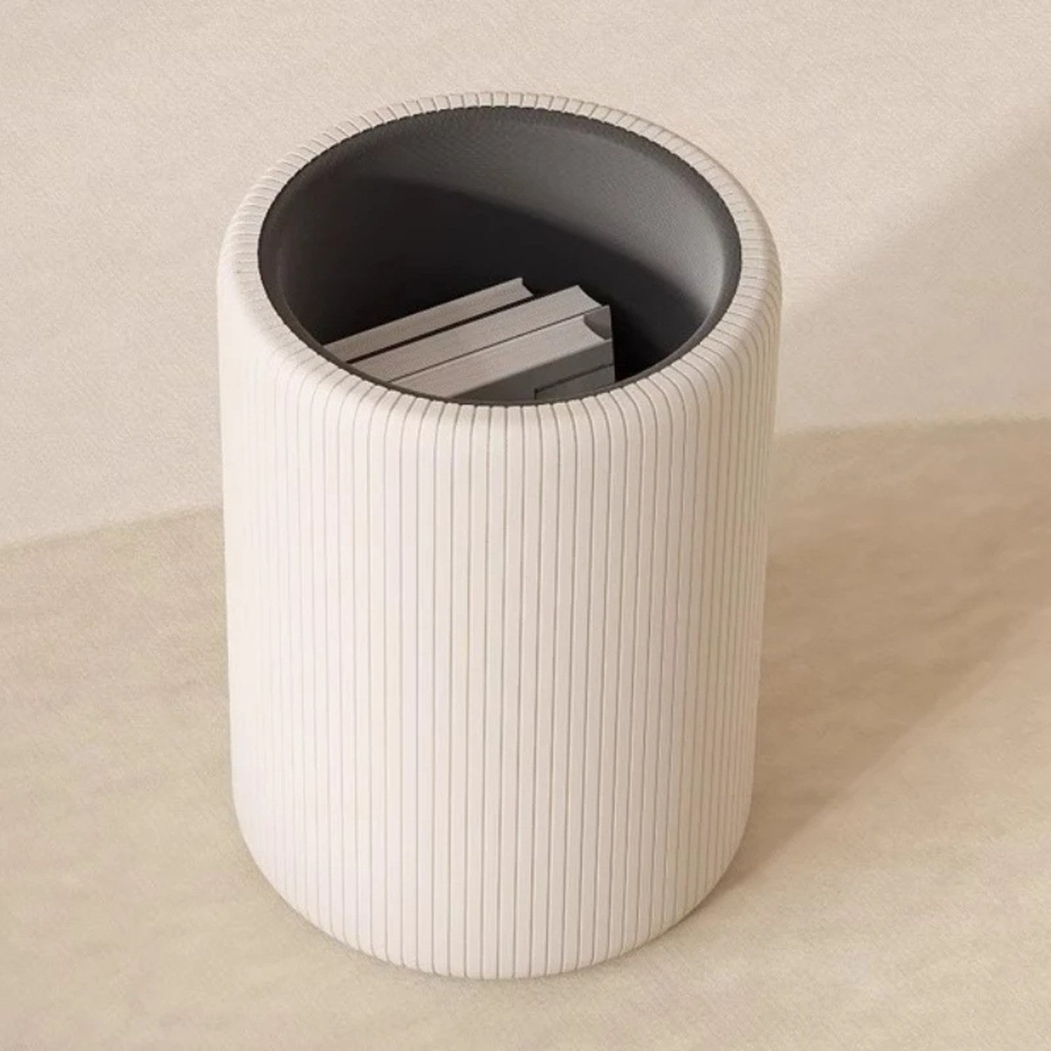 Tabouret de rangement beige ouvert avec des magazines rangés à l'intérieur