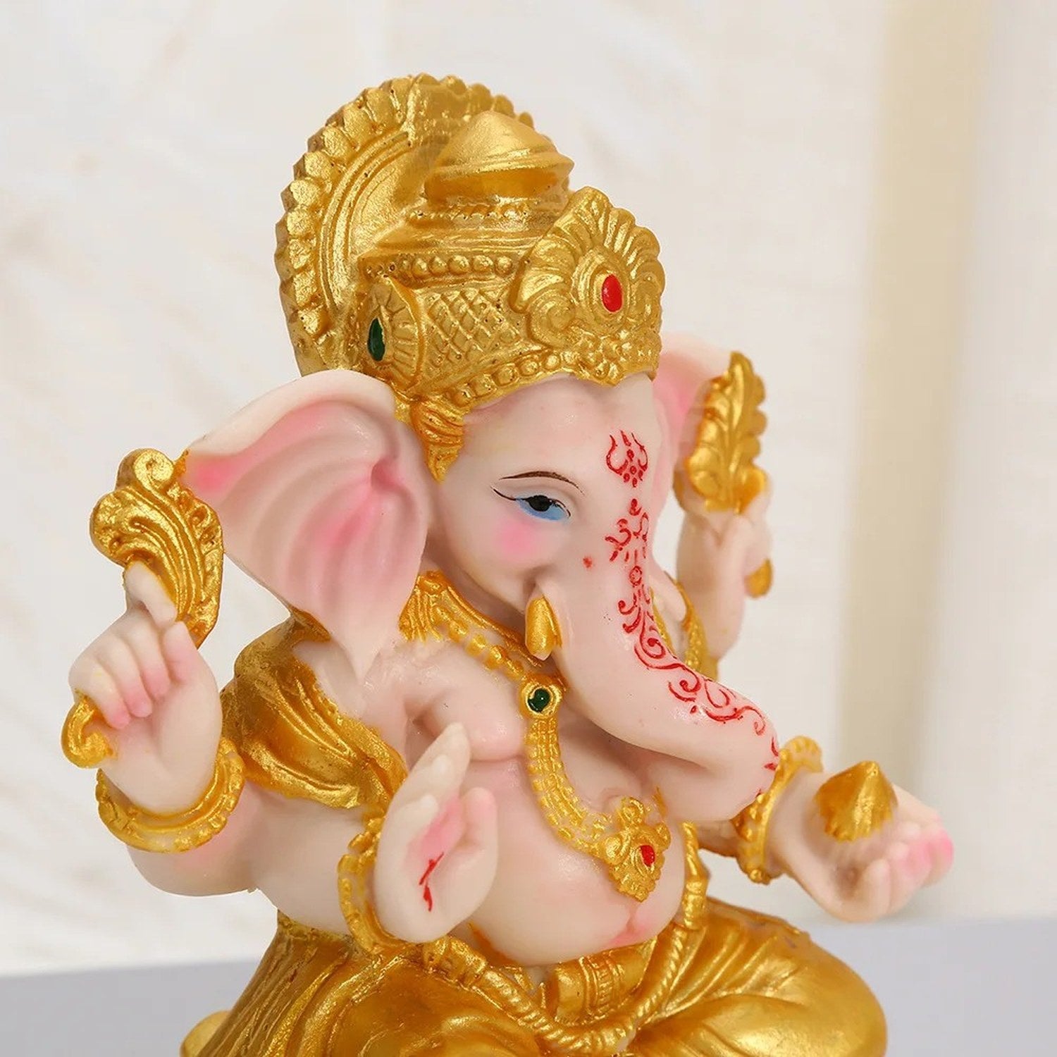 Détail du visage et des ornements dorés de la statue de Ganesha en résine