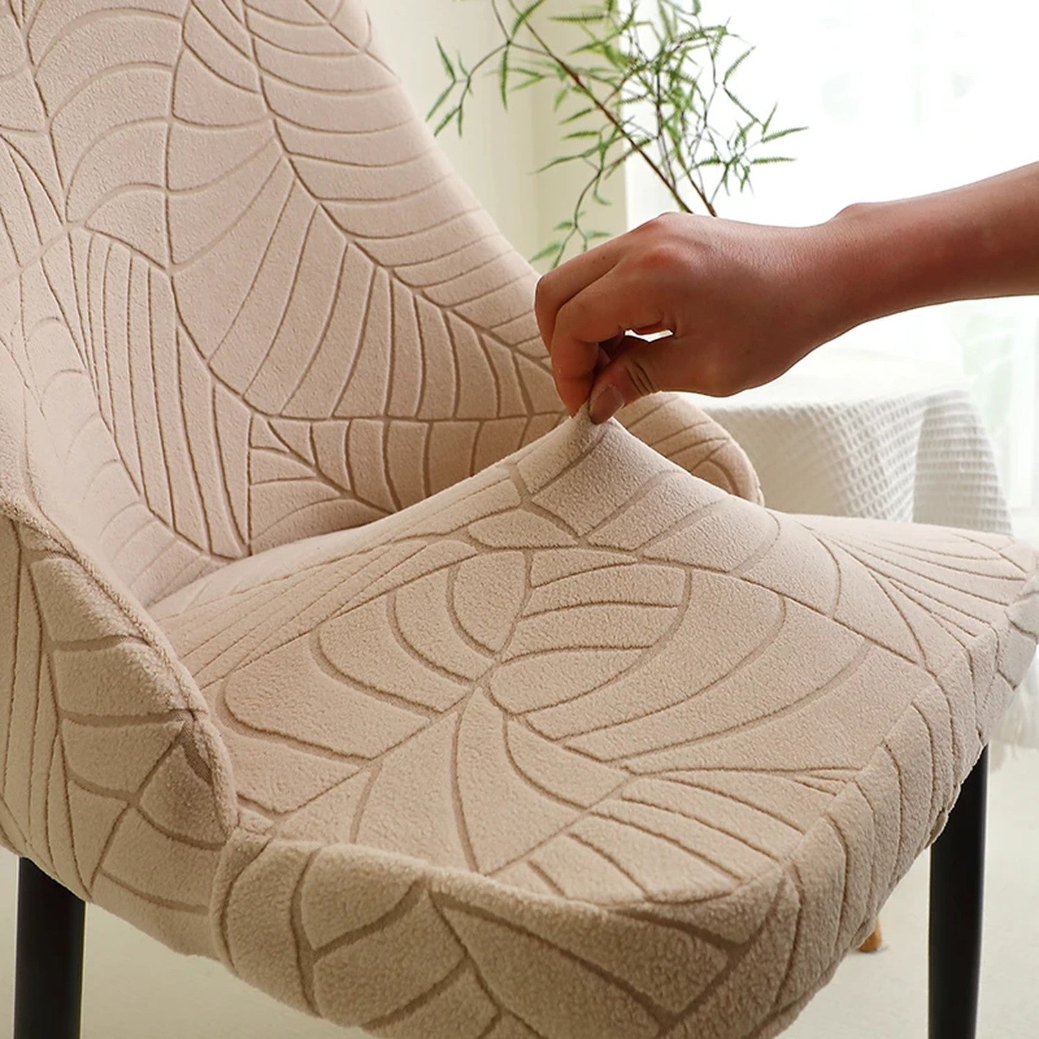 Tissu jacquard beige au motif feuilles étiré à la main montrant l'élasticité de la housse