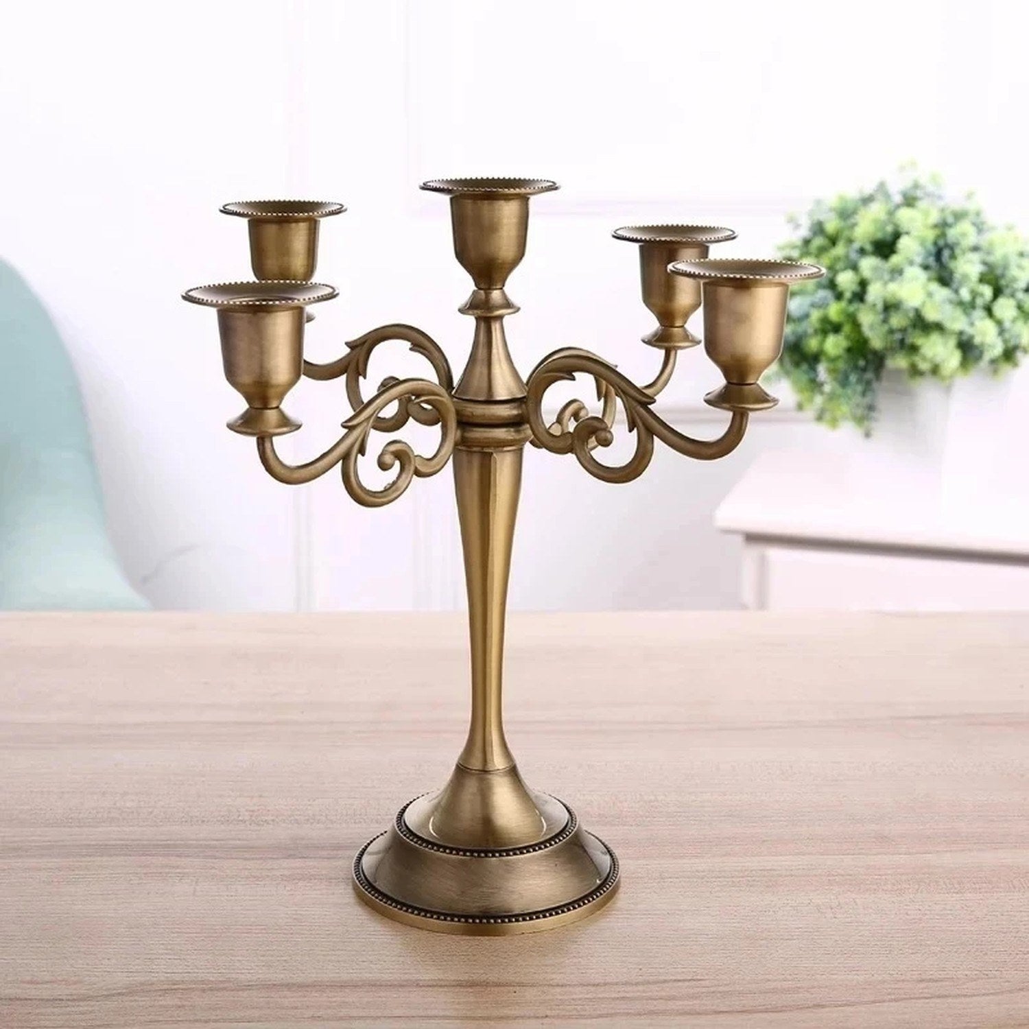 Chandelier épuré en métal bronze à cinq branches posé sur une table en bois
