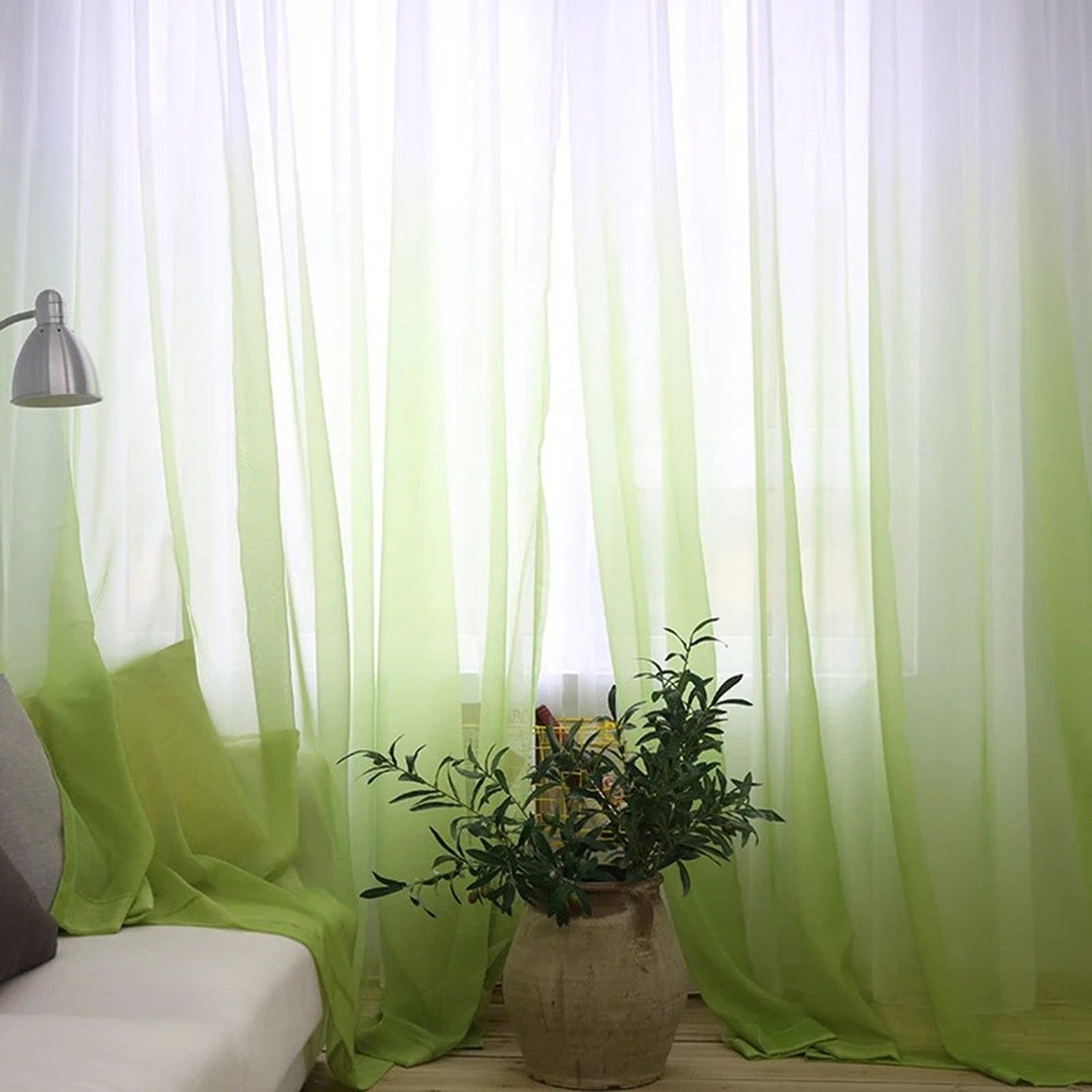 Voilage tulle dégradé vert dans un salon avec fauteuil et plante en pot