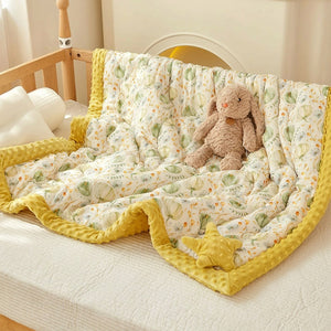 Couette bébé imprimée citrouilles posée sur un lit de berceau avec doudou lapin en peluche