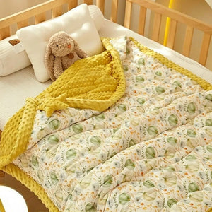 Détail de la couette bébé motif citrouilles pliée dans un berceau