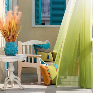 Voilage tulle dégradé vert suspendu sous une pergola extérieure en bois