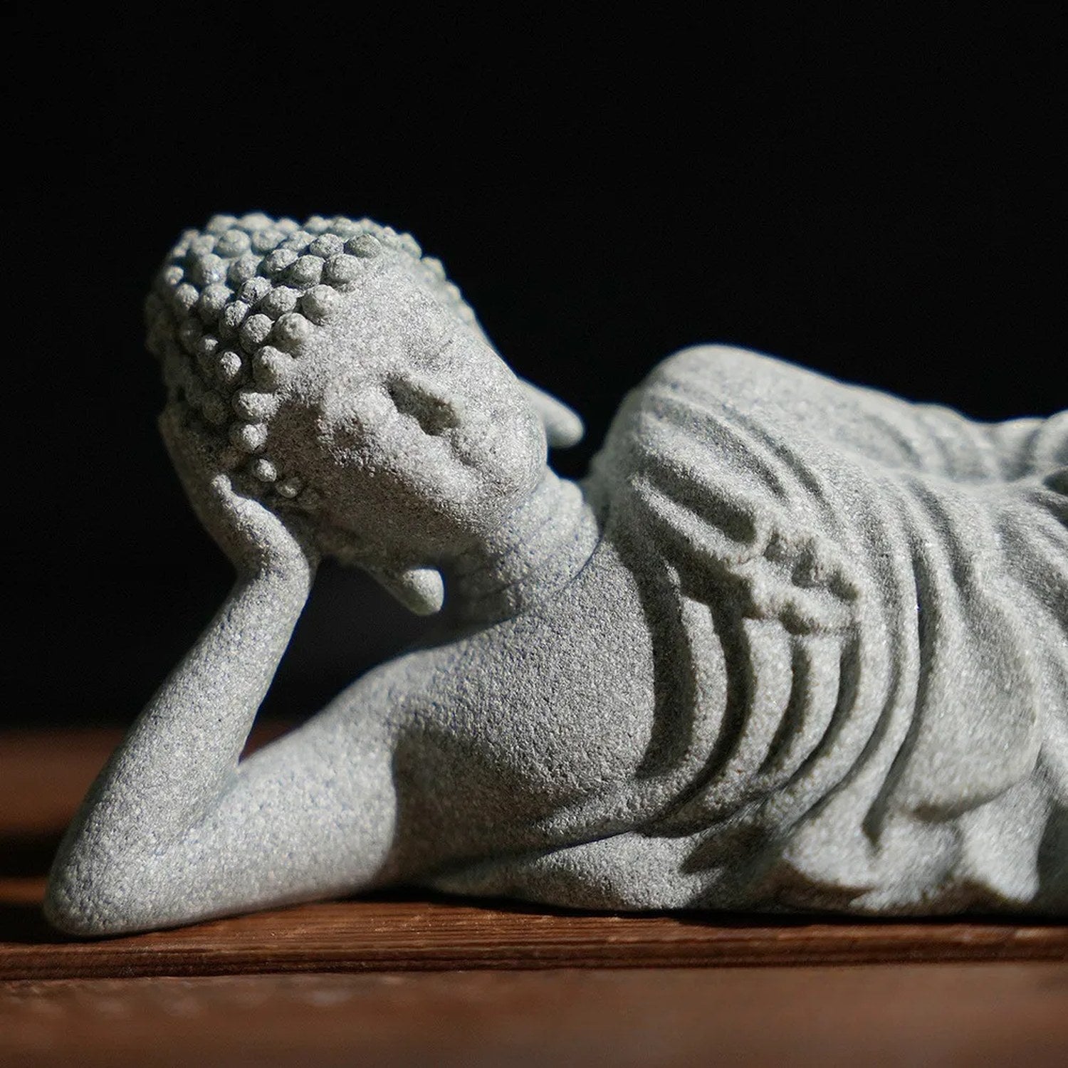 Gros plan sur le visage serein et le drapé sculpté de la statue de Bouddha couché en grès