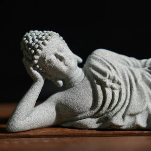 Gros plan sur le visage serein et le drapé sculpté de la statue de Bouddha couché en grès