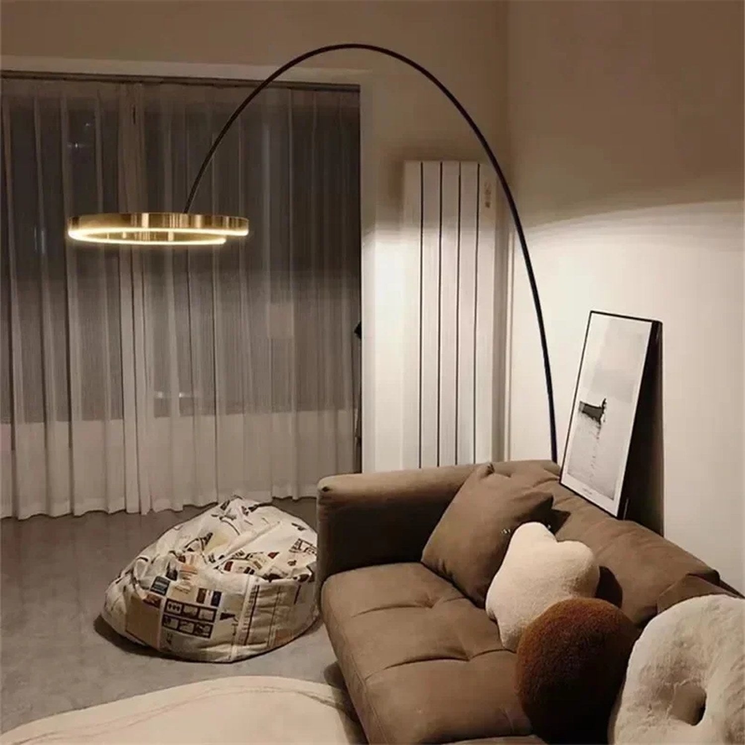 Lampadaire arc doré dans un salon avec canapé marron et rideaux voilage