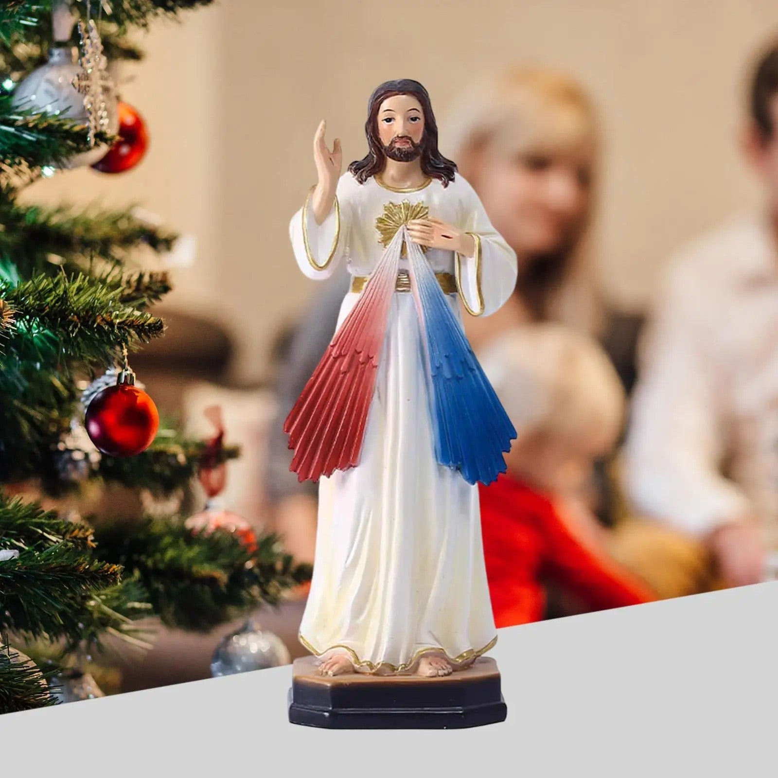 Figurine Jésus Miséricordieux posée devant sapin de Noël décoration