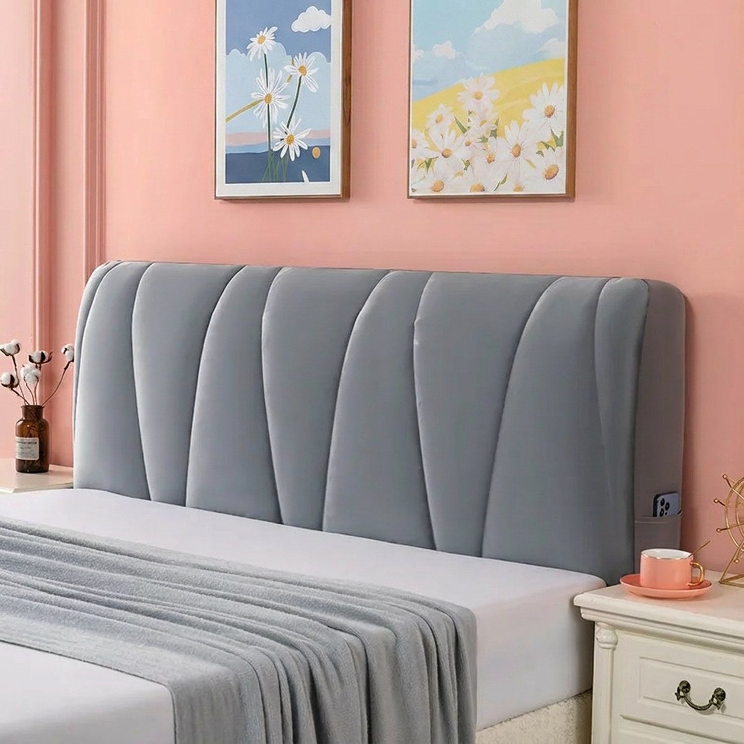 Housse de tête de lit grise capitonnée installée sur un lit dans une chambre chaleureuse