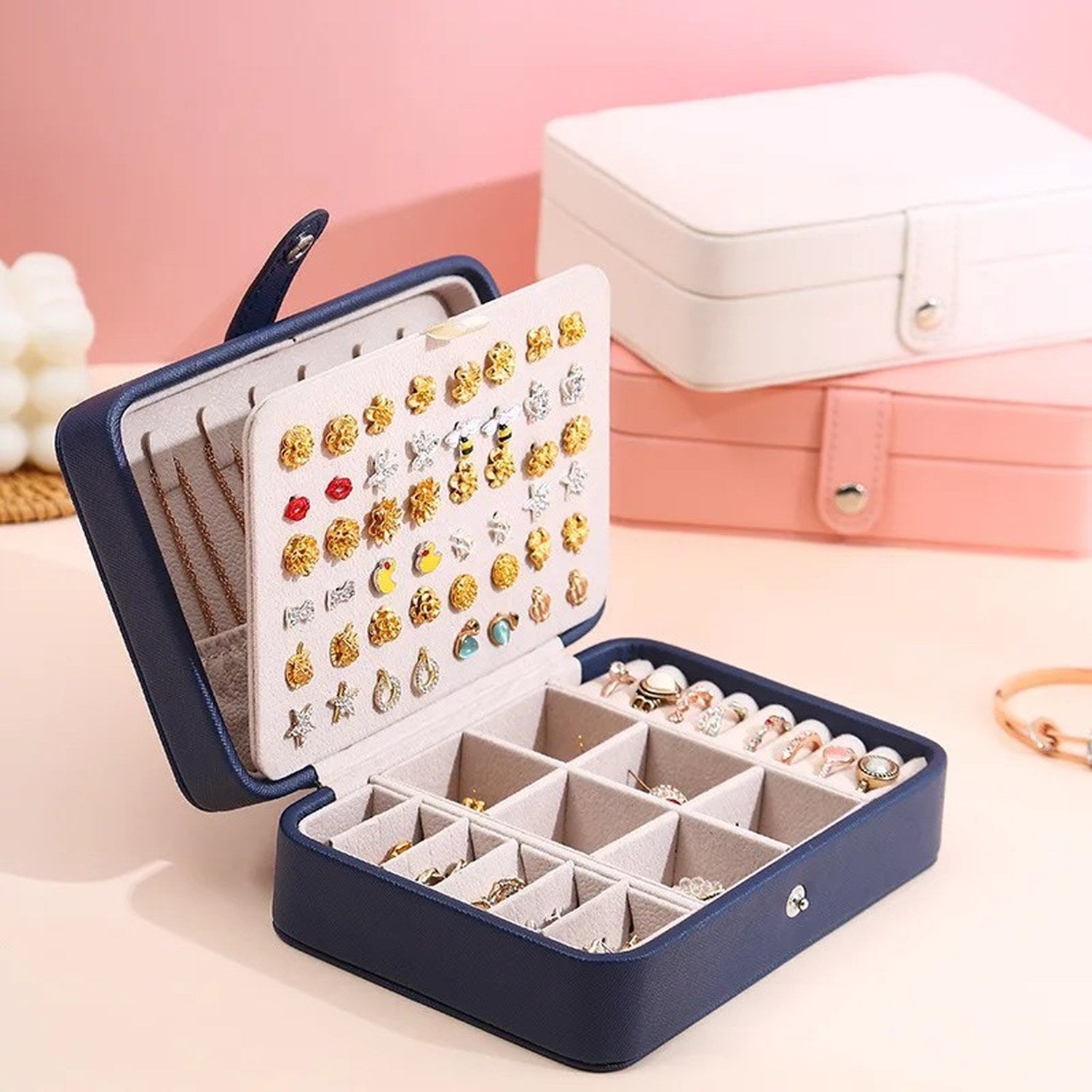 Boîte à bijoux en cuir ouverte avec panneau à boucles d'oreilles et boîtes blanche et rose