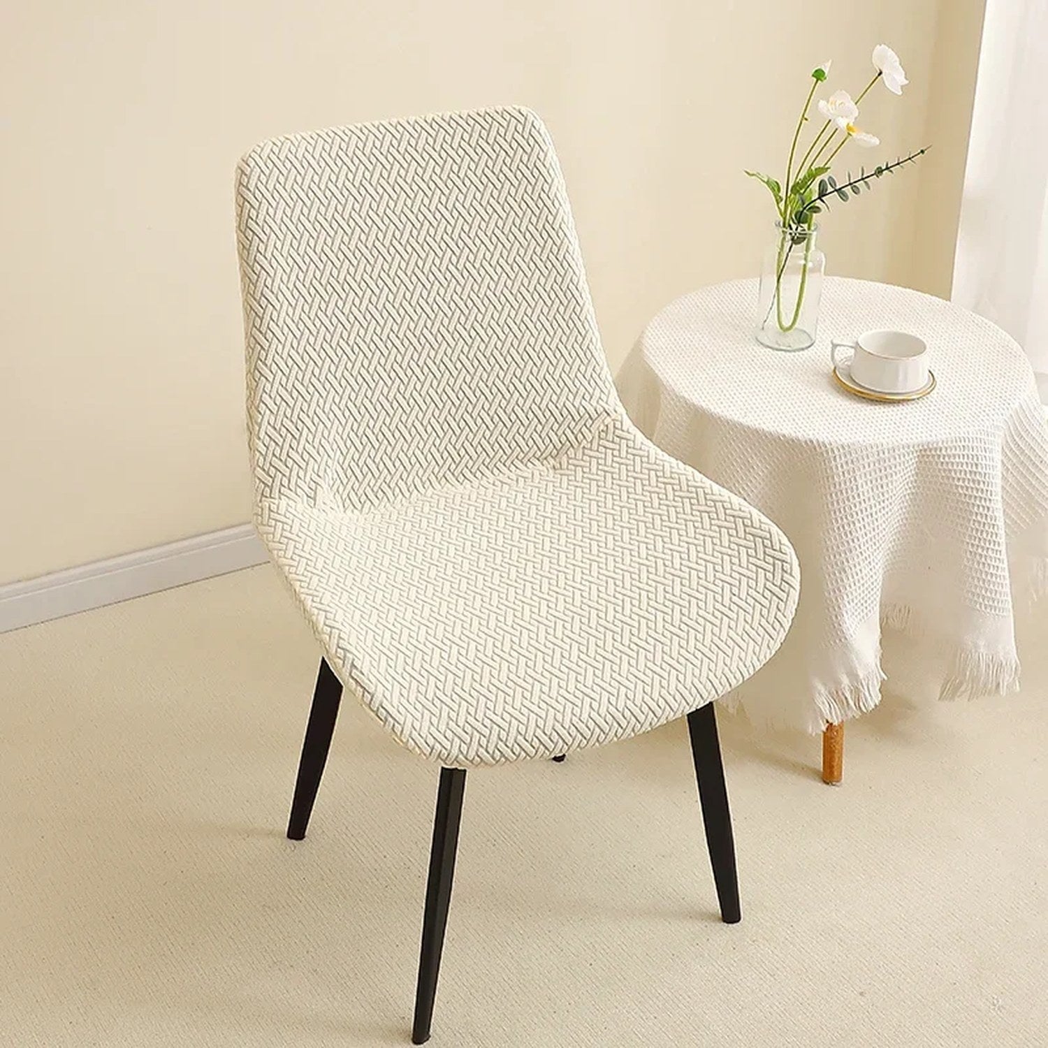 Housse de chaise jacquard ivoire posée sur une chaise près d'une table d'appoint