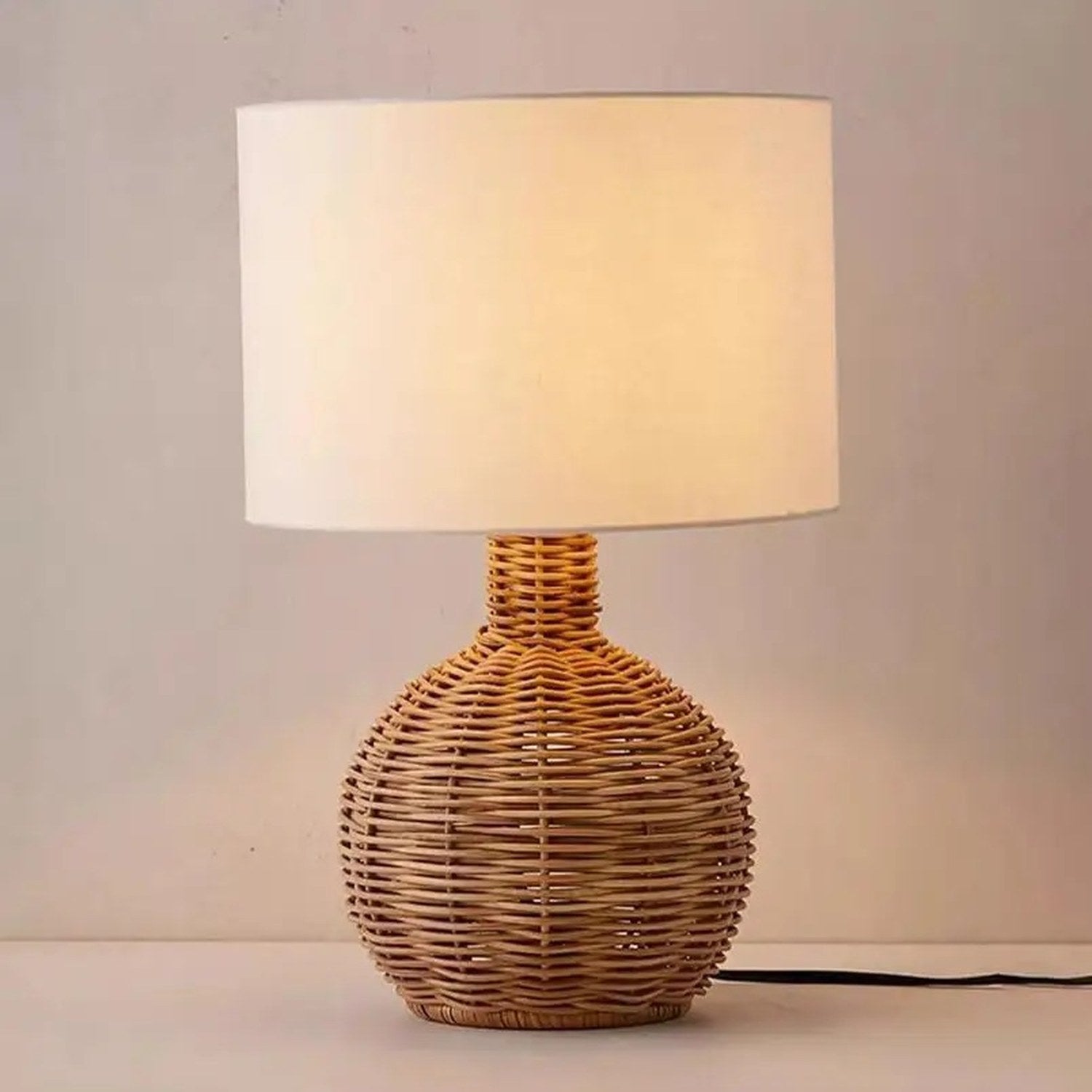 Lampe à poser rotin forme ronde allumée avec fil électrique visible