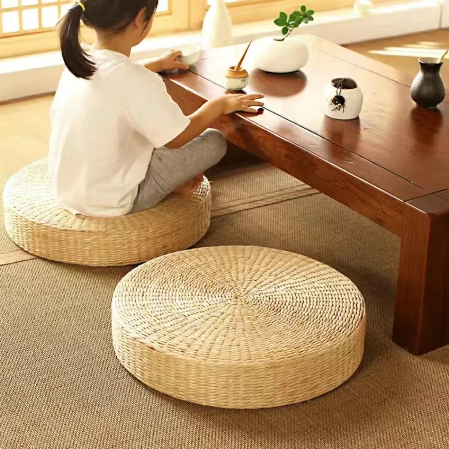 Personne assise sur un pouf en paille devant une table basse zen