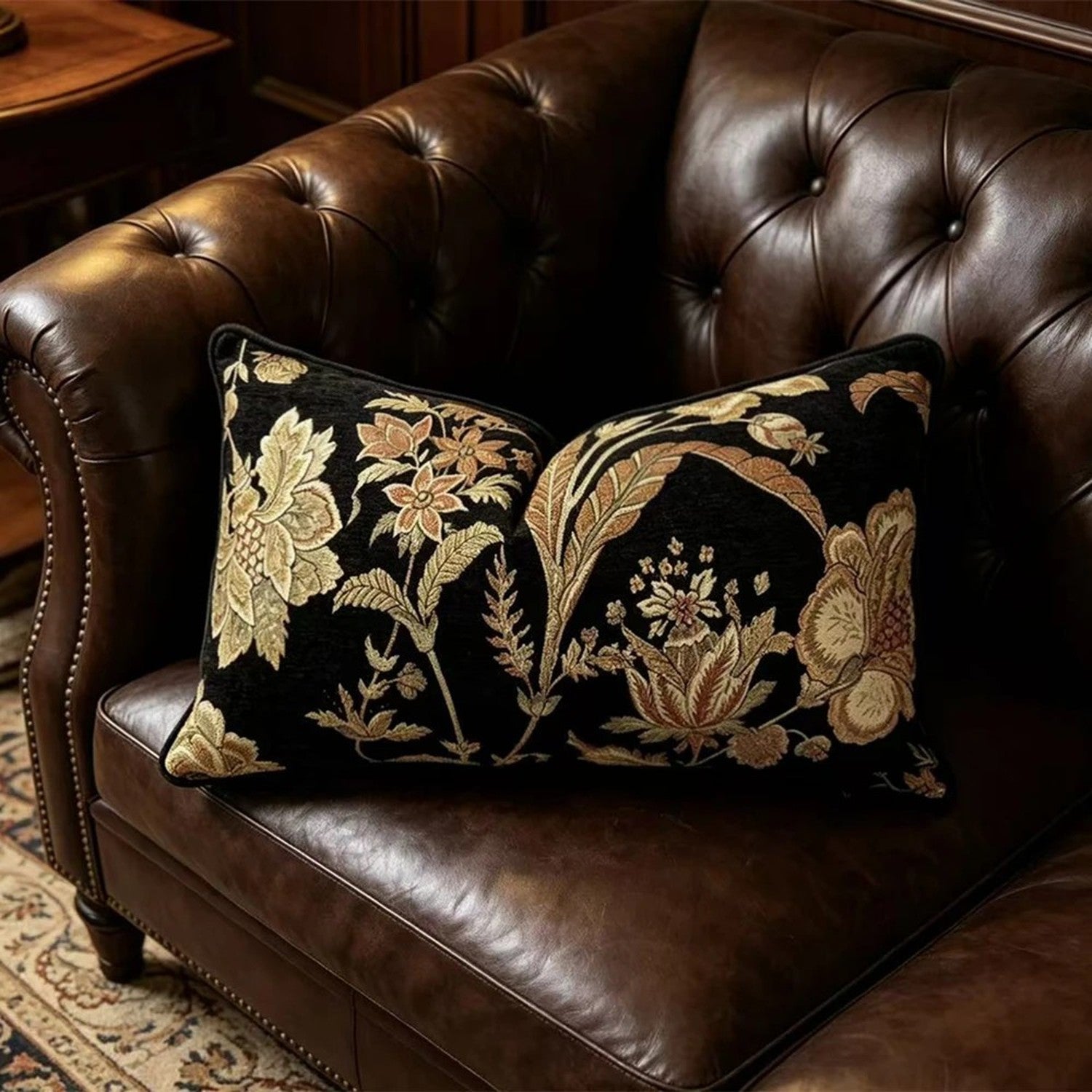 Coussin lombaire a motif floral pose sur un canape en cuir capitonne