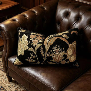 Coussin lombaire a motif floral pose sur un canape en cuir capitonne