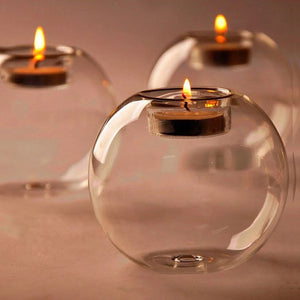 Plusieurs bougeoirs boule en verre transparent allumés côte à côte