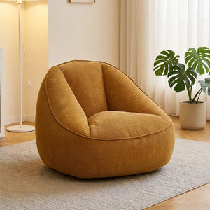 Fauteuil pouf en velours côtelé ambre posé sur un tapis dans un salon