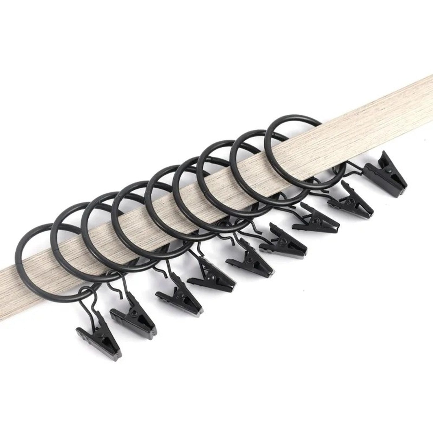 Série d'anneaux à rideau à clips noirs enfilés sur une tringle en bois clair