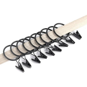 Série d'anneaux à rideau à clips noirs enfilés sur une tringle en bois clair