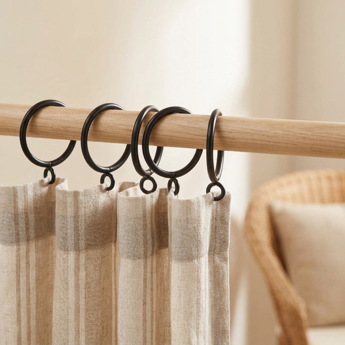 Anneaux à rideau noirs sur tringle en bois avec rideau à rayures beige dans un salon chaleureux