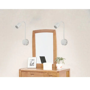 Deux appliques murales blanches encadrant un miroir au dessus d'une commode en bois