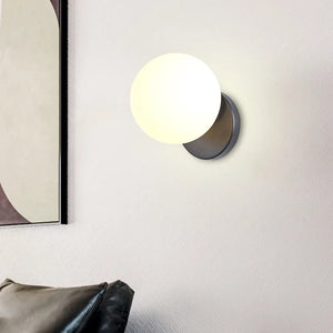 Applique murale boule de verre blanc opale allumée dans un salon moderne