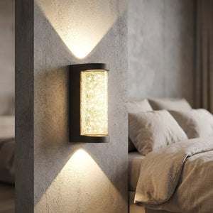 Applique murale effet cristal sur un mur texturé près d'un lit à linge beige
