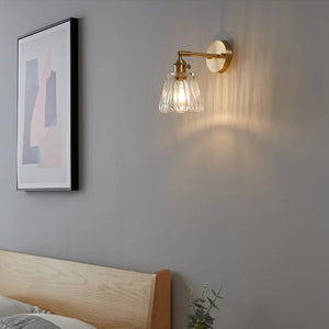 Applique murale en laiton dans une chambre lumineuse avec tête de lit en bois et plante