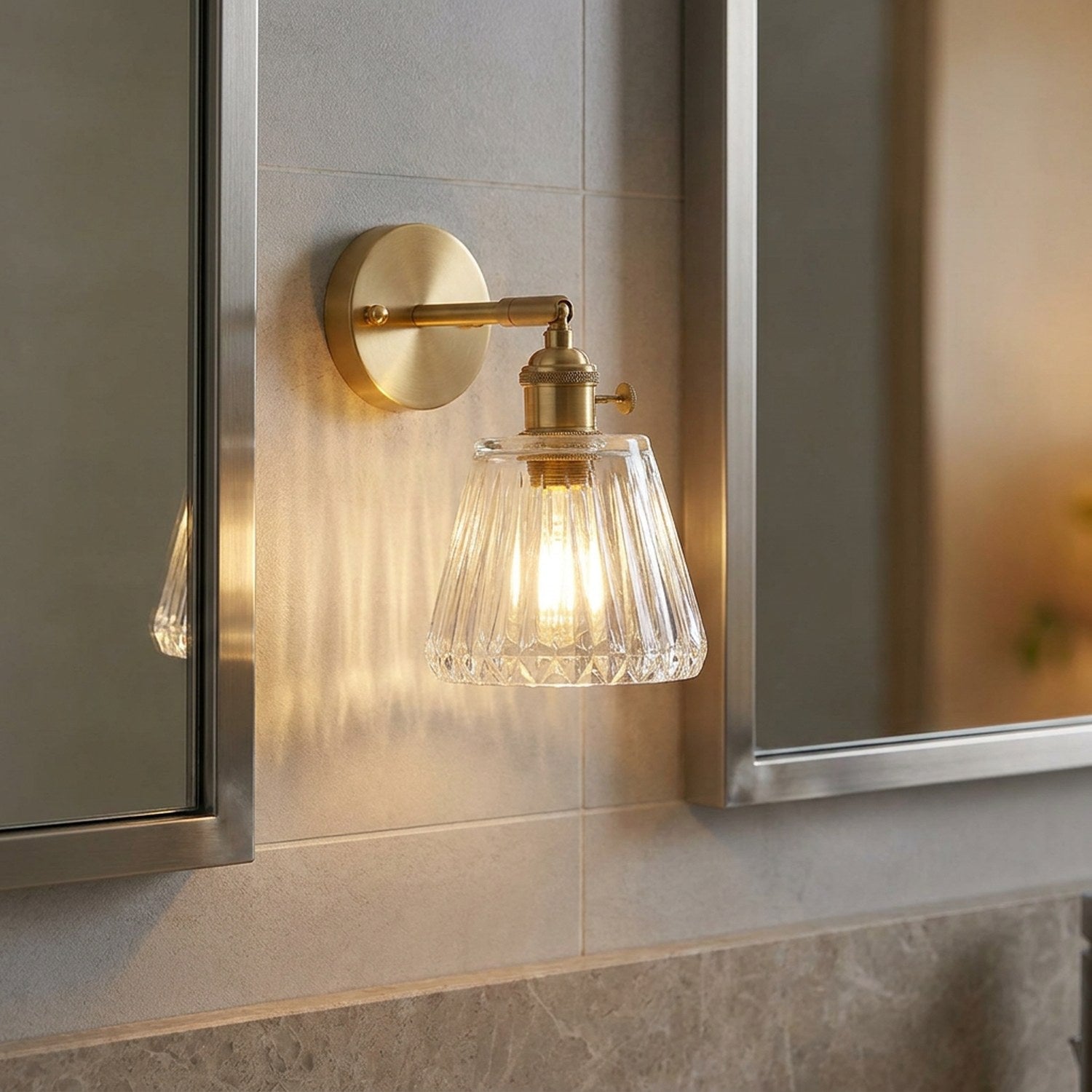 Applique murale en laiton dans une salle de bain avec carrelage gris et miroir