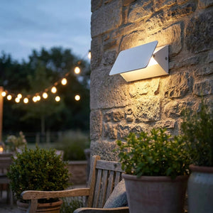 Applique murale LED blanche installée en extérieur sur une terrasse en pierre le soir