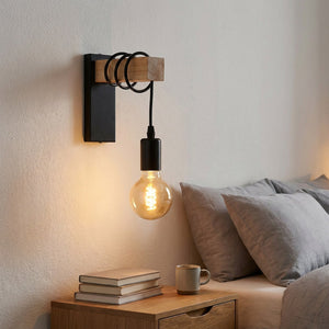 Applique murale noire installée au-dessus d'une table de chevet dans une chambre cosy