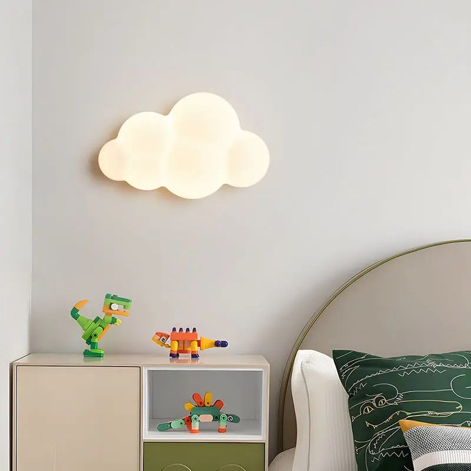 Applique murale en forme de nuage blanche allumée au dessus d'un meuble avec jouets dans une chambre d'enfant