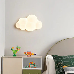 Applique murale en forme de nuage blanche allumée au dessus d'un meuble avec jouets dans une chambre d'enfant