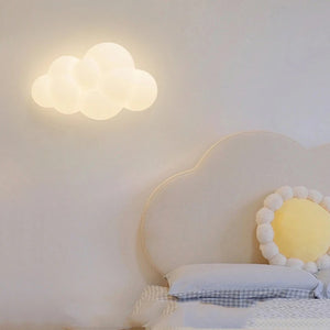 Applique murale nuage allumée au dessus d'une tête de lit arrondie dans une chambre enfant