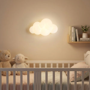 Applique murale nuage allumée au-dessus d'un berceau dans une chambre de bébé douce