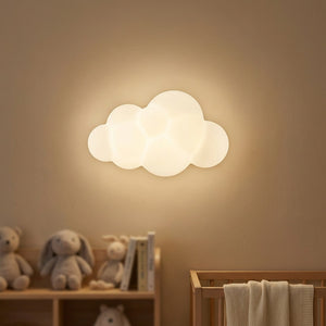 Applique murale en forme de nuage rebondi diffusant une lumière chaude sur le mur d'une chambre d'enfant