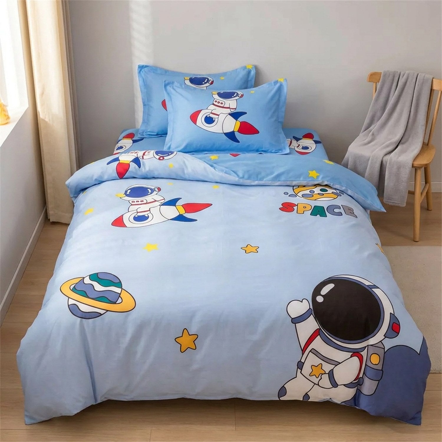 Parure de lit enfant astronaute dans une chambre cocooning avec chaise en bois et plaid