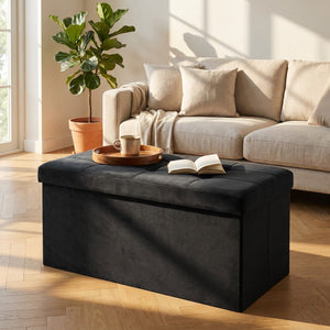 Banc coffre en velours noir utilisé comme table basse avec plateau et livre