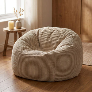 Pouf beige en velours côtelé posé au sol près d'une fenêtre